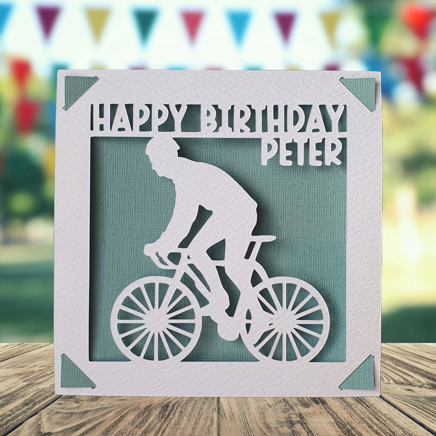 A personalised birthday card with a white background featuring a silhouette of a person on a bicycle, with a teal background.