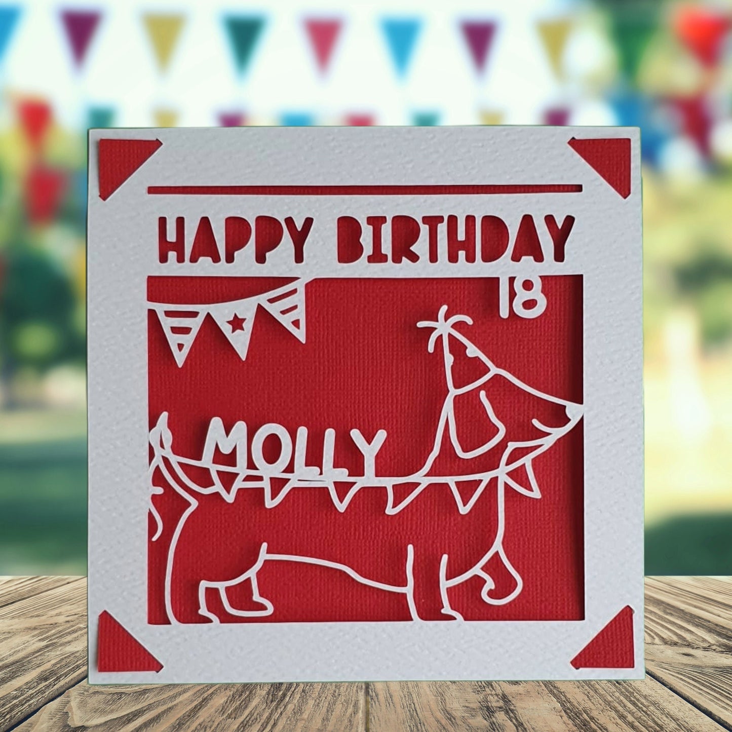 A personalised birthday card with a sausage dog illustration, made from white and red coloured card, with the text 'Happy Birthday' and a space to add a name and age if required.