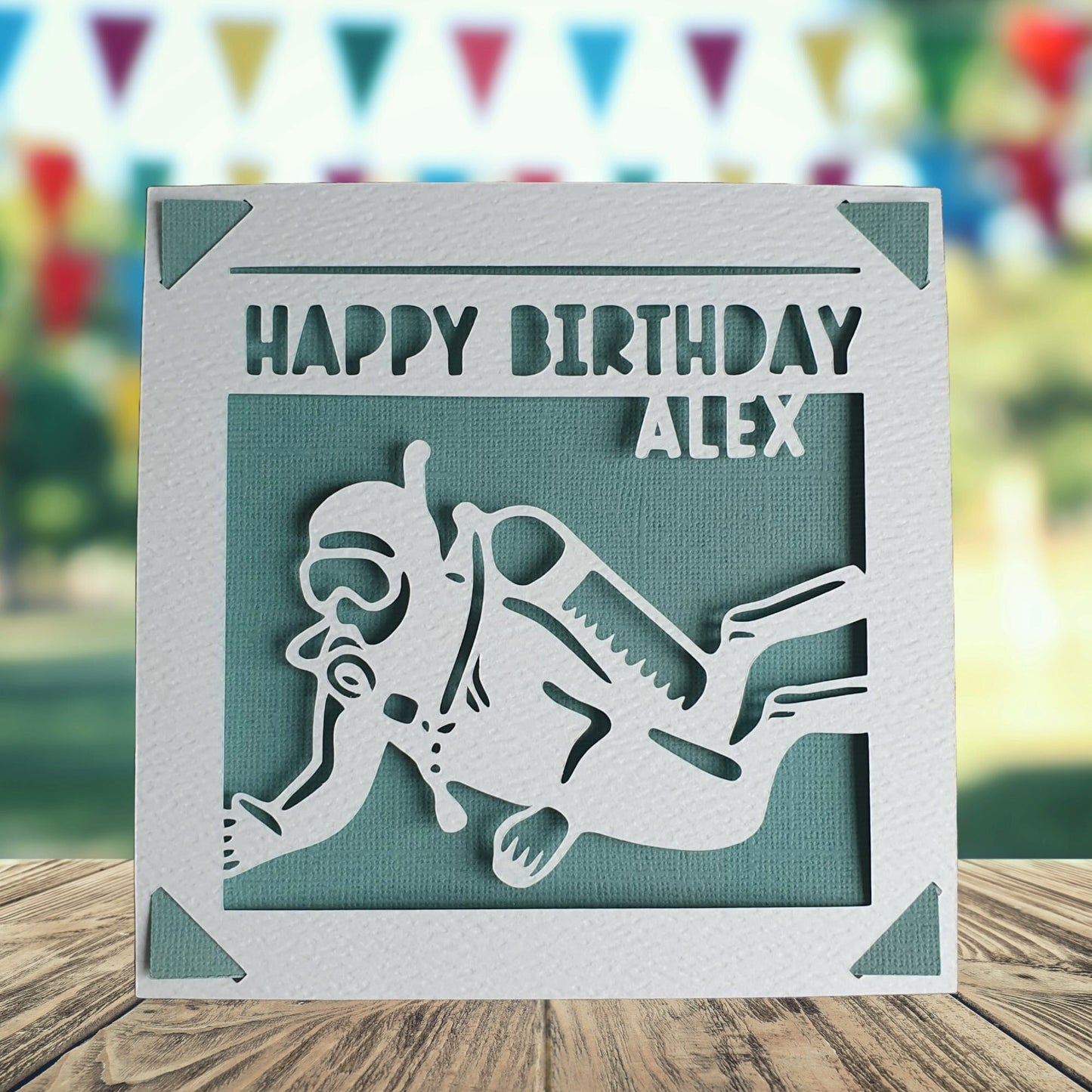 A personalised birthday card featuring a cut out of a scuba diver, with the text 'Happy Birthday' and a space to add a name and age if required. The card has a teal background colour.