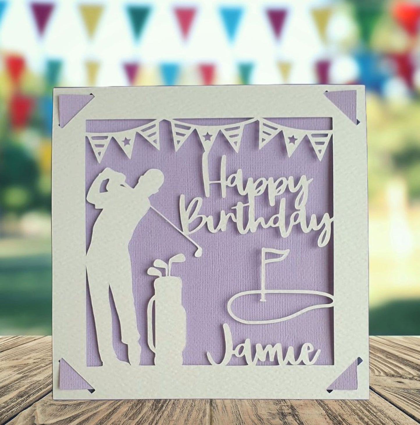 A personalised golfing birthday card for someone who loves golf. The card is fully customisable with the recipient's name. The card features a figure playing golf, with their golf club, bag and a cut out of a golf hole with flag. The background colour is purple.