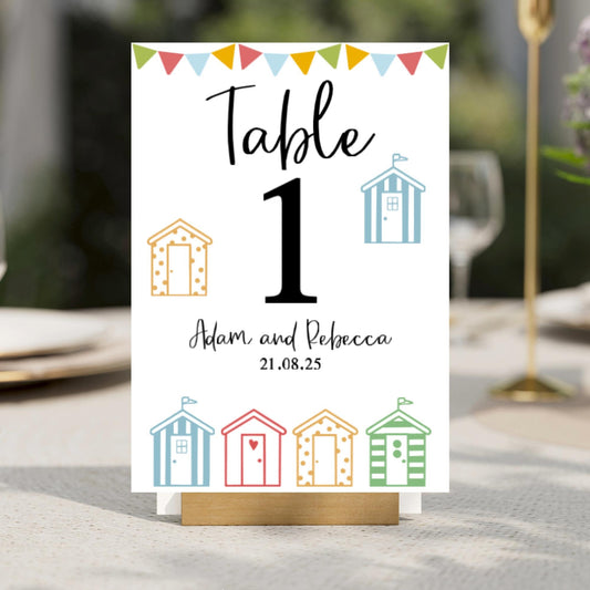 A Table number for a wedding table with beach hut designs on it.