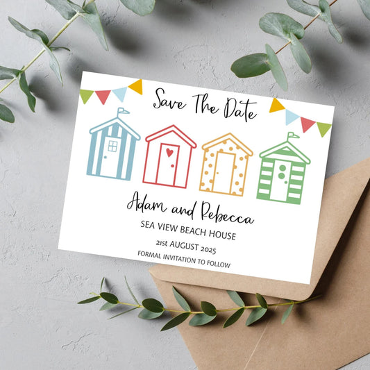 A colourful save the date wedding invitation with beach hut designs, personalized with names and wedding date, displayed next to a brown envelope.
