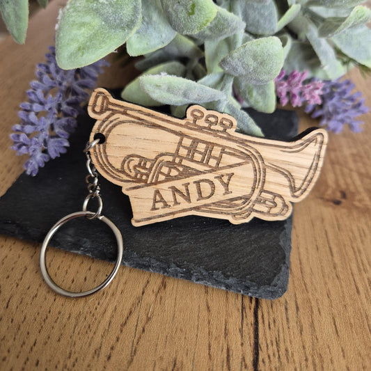 A Brass band themed wooden keyring in the shape of a cornet or trumpet with a name on it.