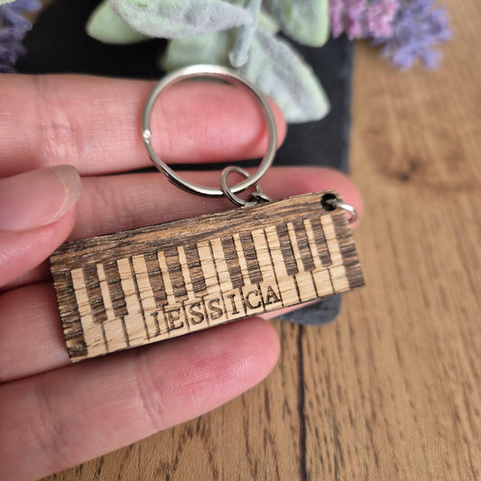 Personalised piano keyring made from wood and engraved with a name.