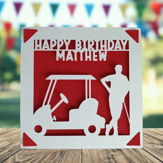 A personalised birthday card with a silhouette of a person standing next to a golf buggy, with the text 'Happy Birthday' and a space to add a name and age if required. The background is red.