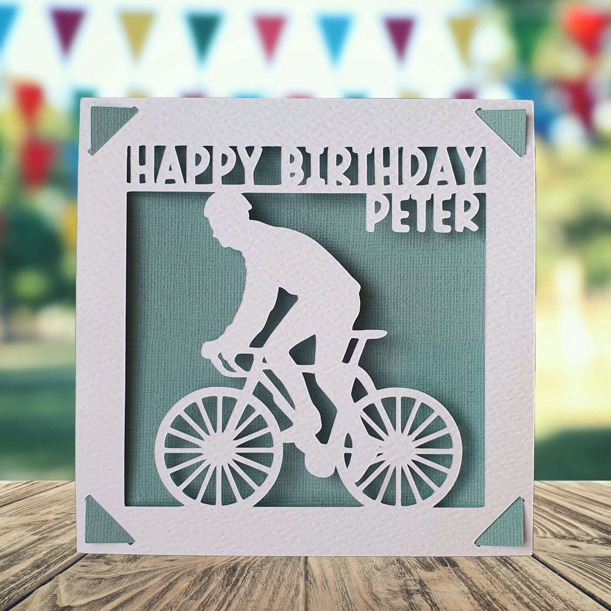 A personalised birthday card with a white background featuring a silhouette of a person on a bicycle, with a teal background.