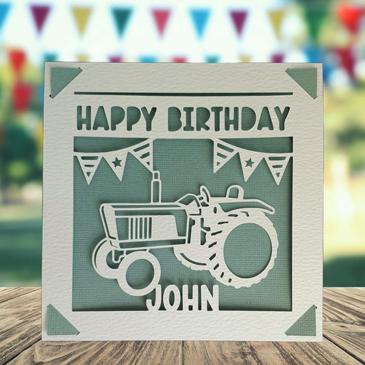 A personalised greeting birthday card with a tractor on the front. Text saying 'happy birthday' with the space to add a name and age. Card background is a teal colour.